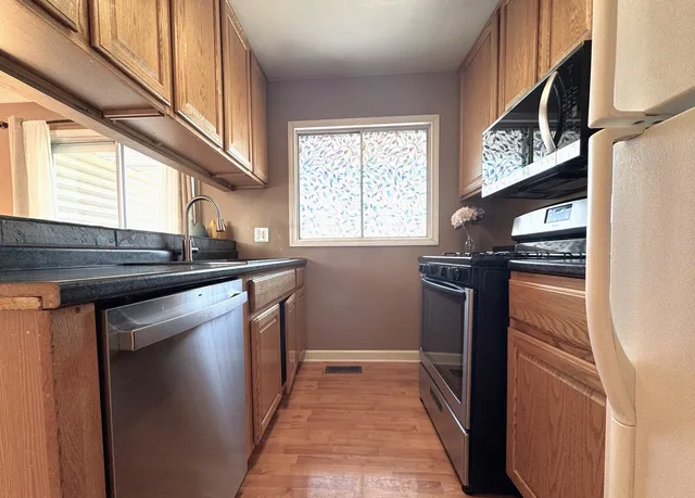 a kitchen with stainless steel appliances granite countertop a sink and a refrigerator