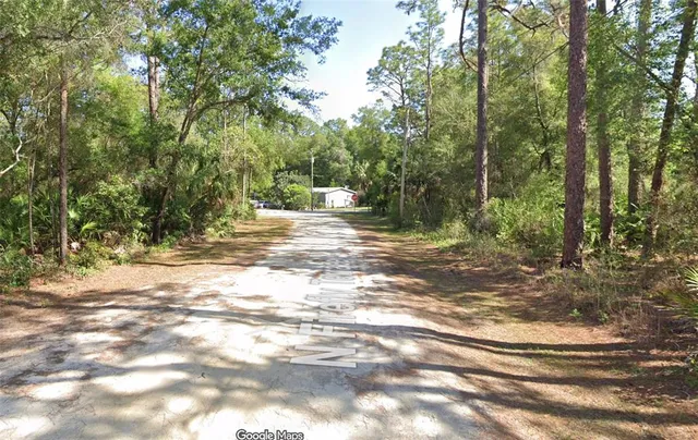 an aerial view of residential house with outdoor space and trees all around