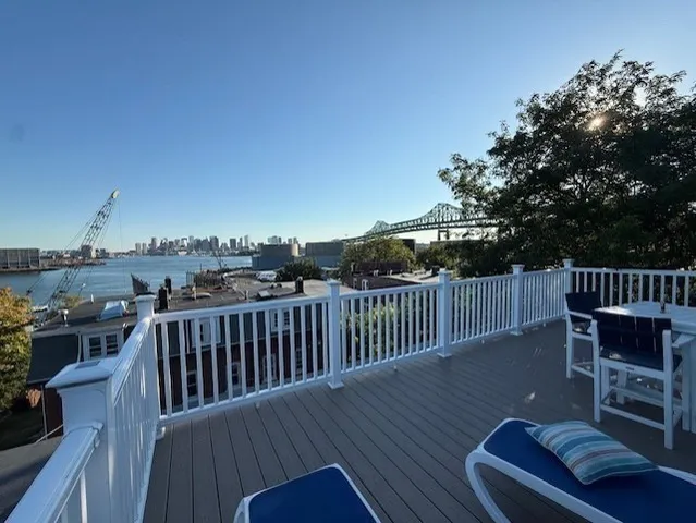 a view of a roof deck with table and chairs with wooden floor and fence