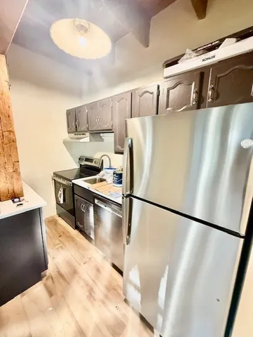 a kitchen with stainless steel appliances granite countertop a refrigerator a stove a sink and a microwave