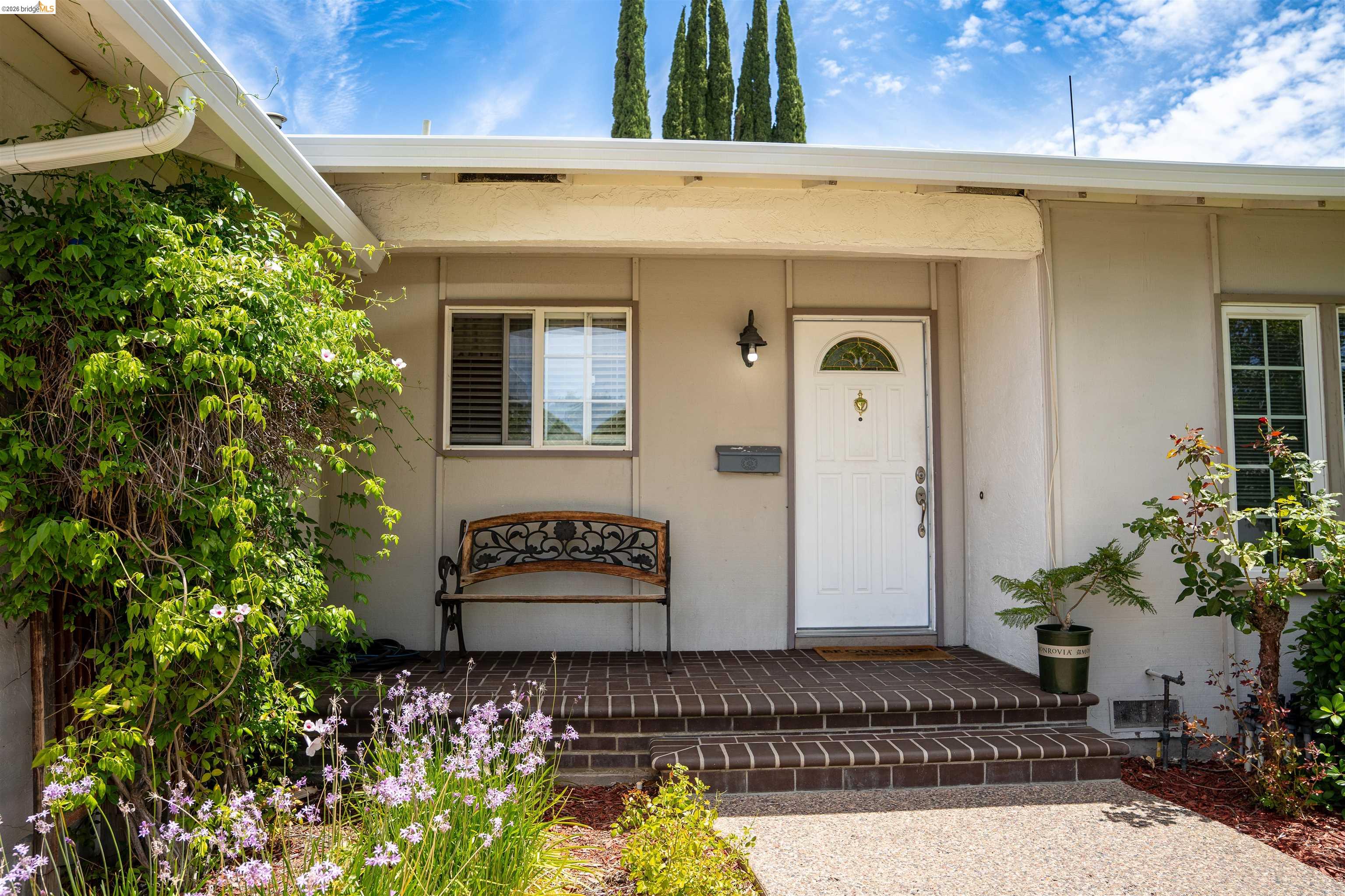 3513 Rio Grande Drive Antioch, CA 94509 - Photo 3 of 22 Welcoming front entry featuring a white paneled door with an arched window, brick steps, a coordinating brick porch, exterior wall sconce, and mature landscaping