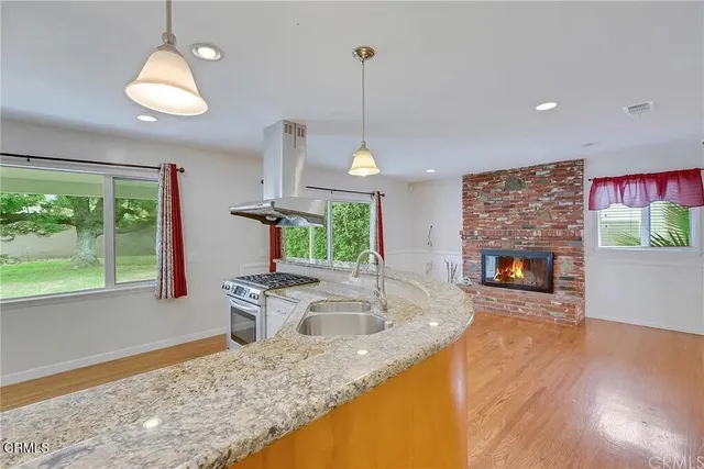a kitchen with kitchen island granite countertop a sink a counter top space appliances and a window