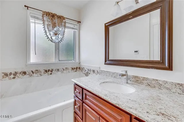 a bathroom with a granite countertop sink and a mirror