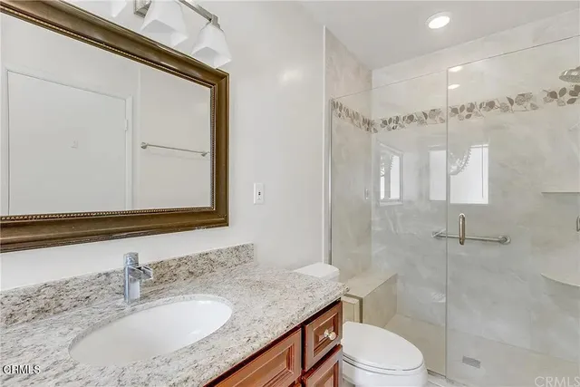 a bathroom with a granite countertop sink toilet a mirror and shower