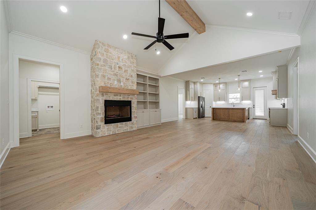 a view of a livingroom with a fireplace a ceiling fan and wooden floor