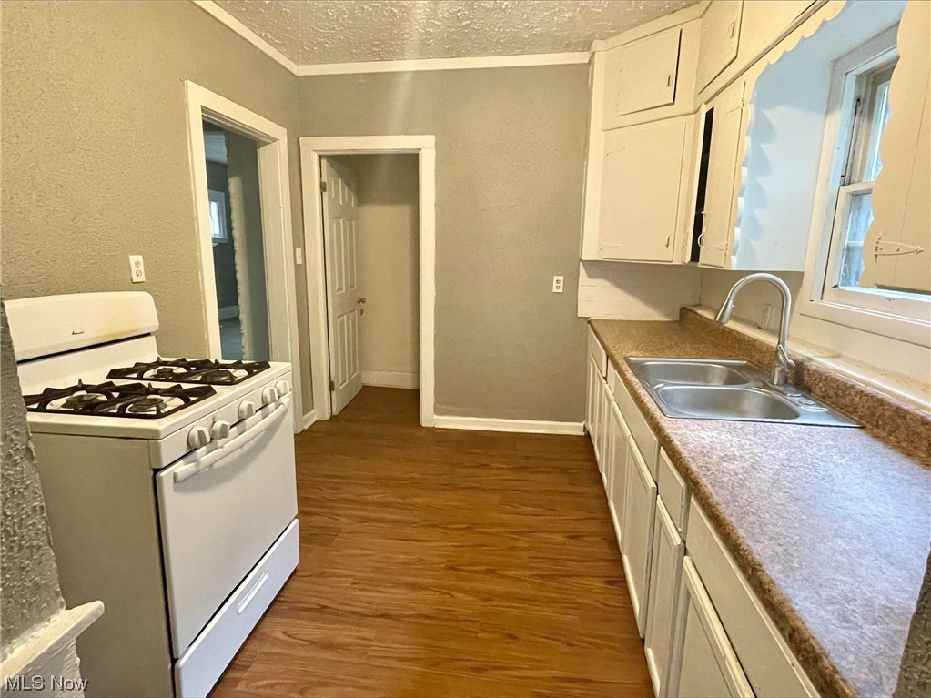 857 Aberdeen Street Akron, OH 44310 - Photo 7 of 23 Kitchen featuring sink, white range with gas stovetop, a textured ceiling, dark hardwood floors, and white cabinetry