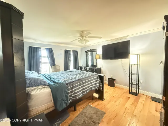 a spacious bedroom with a bed and a flat tv screen on dresser
