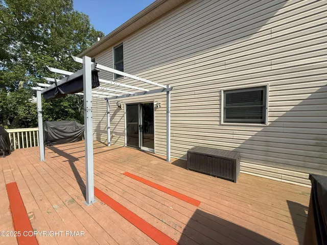 a backyard of a house with wooden floor and fence and a large tree