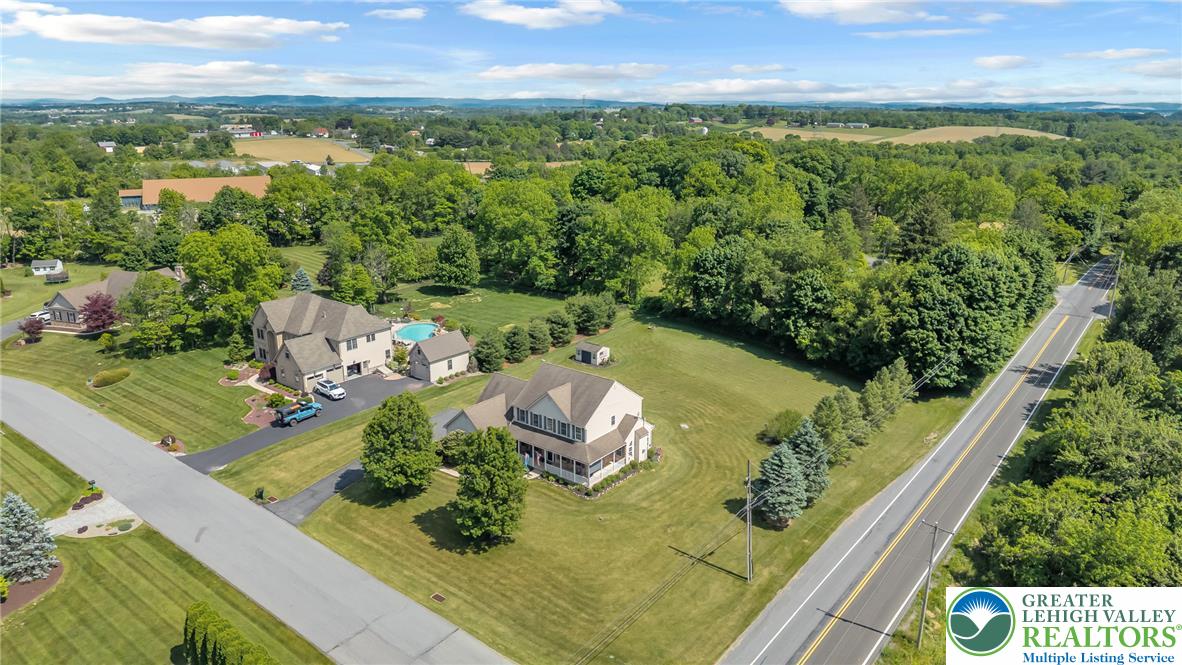 204 Bushkill Ridge Road Wind Gap, PA 18091 - Photo 4 of 48 An aerial perspective showcases a large residential property nestled amongst verdant trees, with expansive lawns and distant vistas.