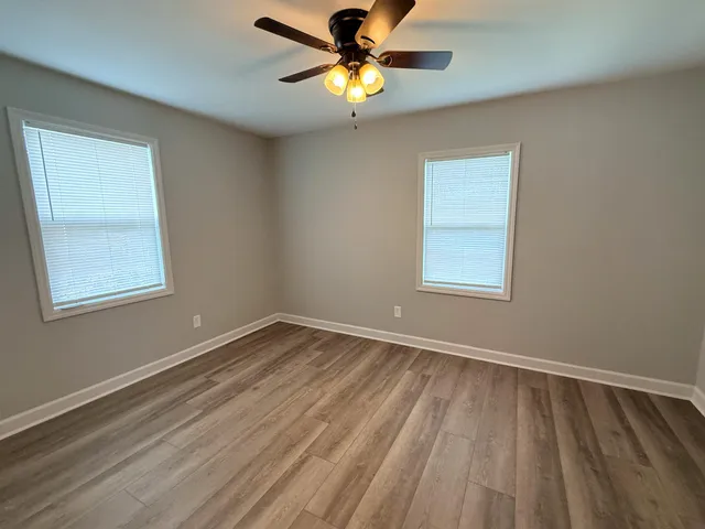 a view of an empty room with window and a chandelier fan
