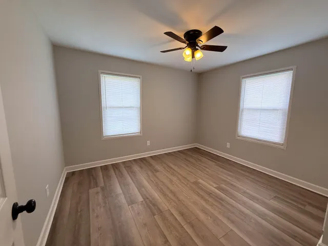 a view of empty room with wooden floor and fan