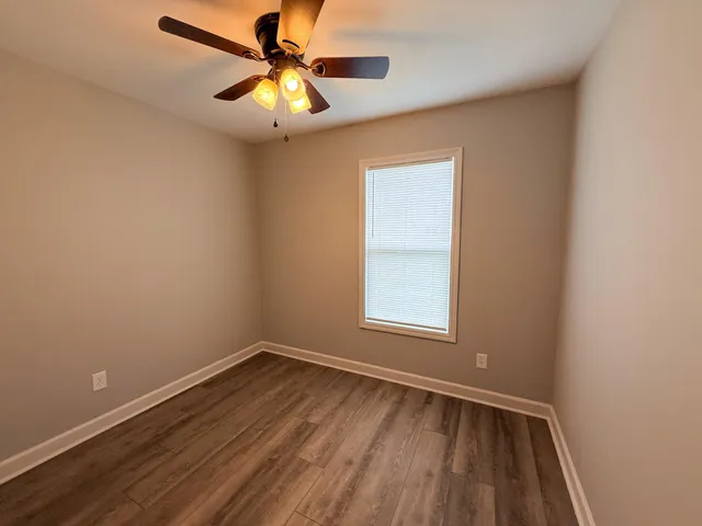 an empty room with a window and a fan
