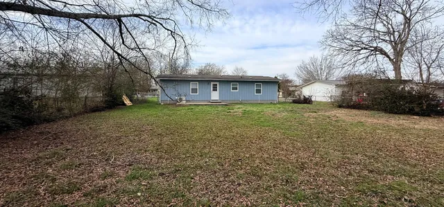 a view of house with yard and trees in the background