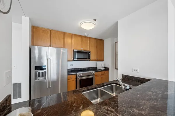 a kitchen with stainless steel appliances granite countertop a sink a stove a refrigerator a washer dryer and a refrigerator