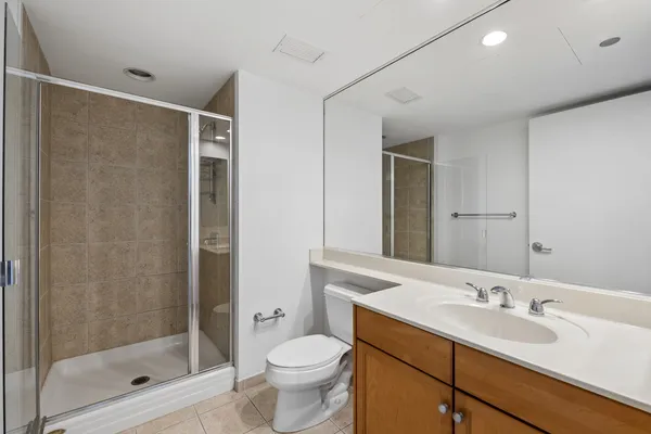 a bathroom with a shower sink vanity mirror and toilet