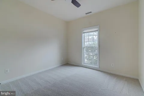a view of an empty room with wooden floor fireplace and a window