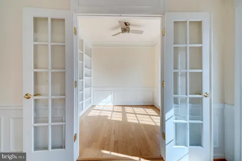 a hallway with white doors wooden floor and front door