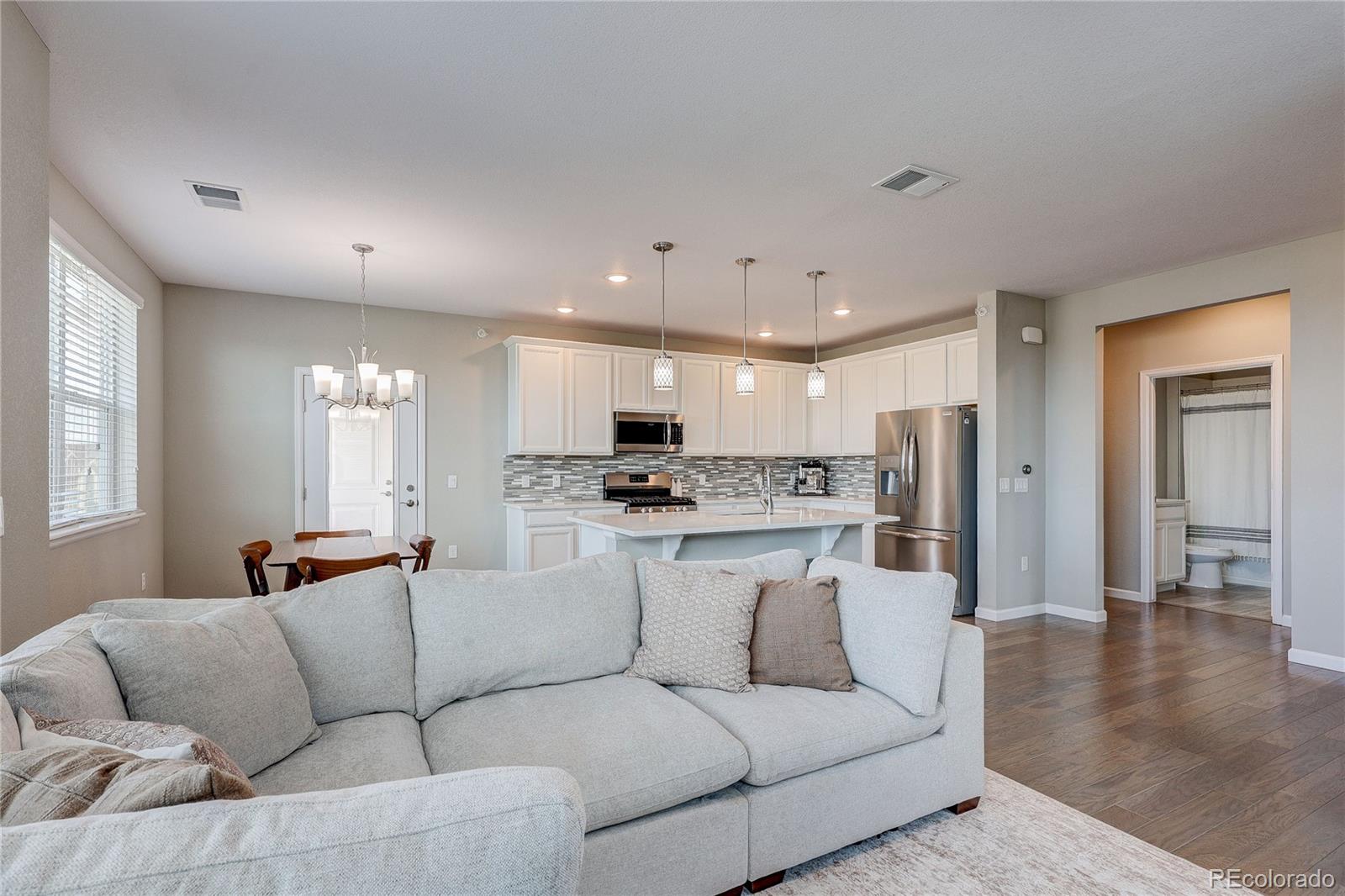 4777 Copeland Circle, Unit 204 Highlands Ranch, CO 80126 - Photo 11 of 39 a living room with white couches and kitchen view with wooden floor