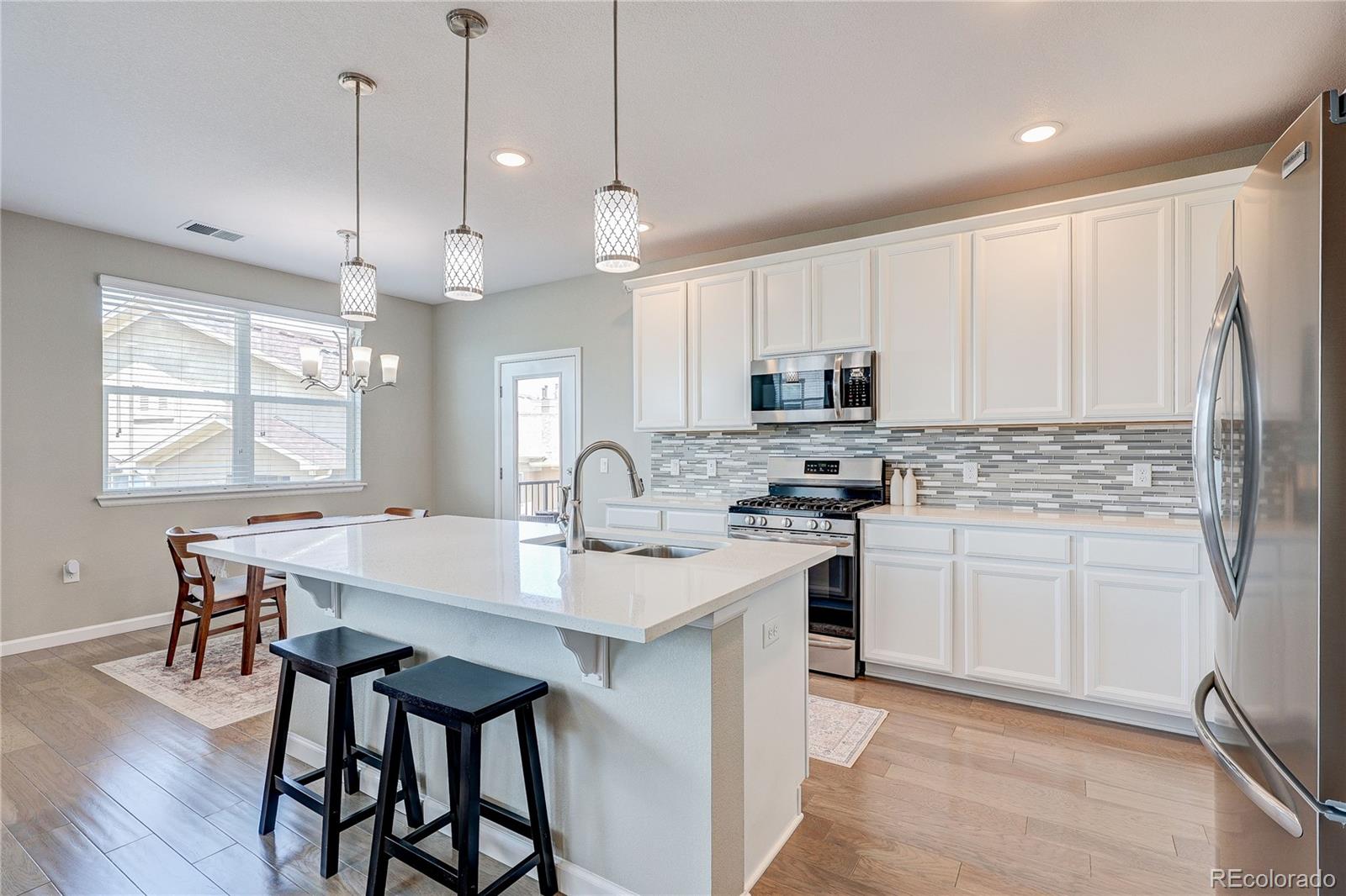 4777 Copeland Circle, Unit 204 Highlands Ranch, CO 80126 - Photo 12 of 39 a kitchen with stainless steel appliances granite countertop a stove a sink a microwave a refrigerator and white cabinets with wooden floor