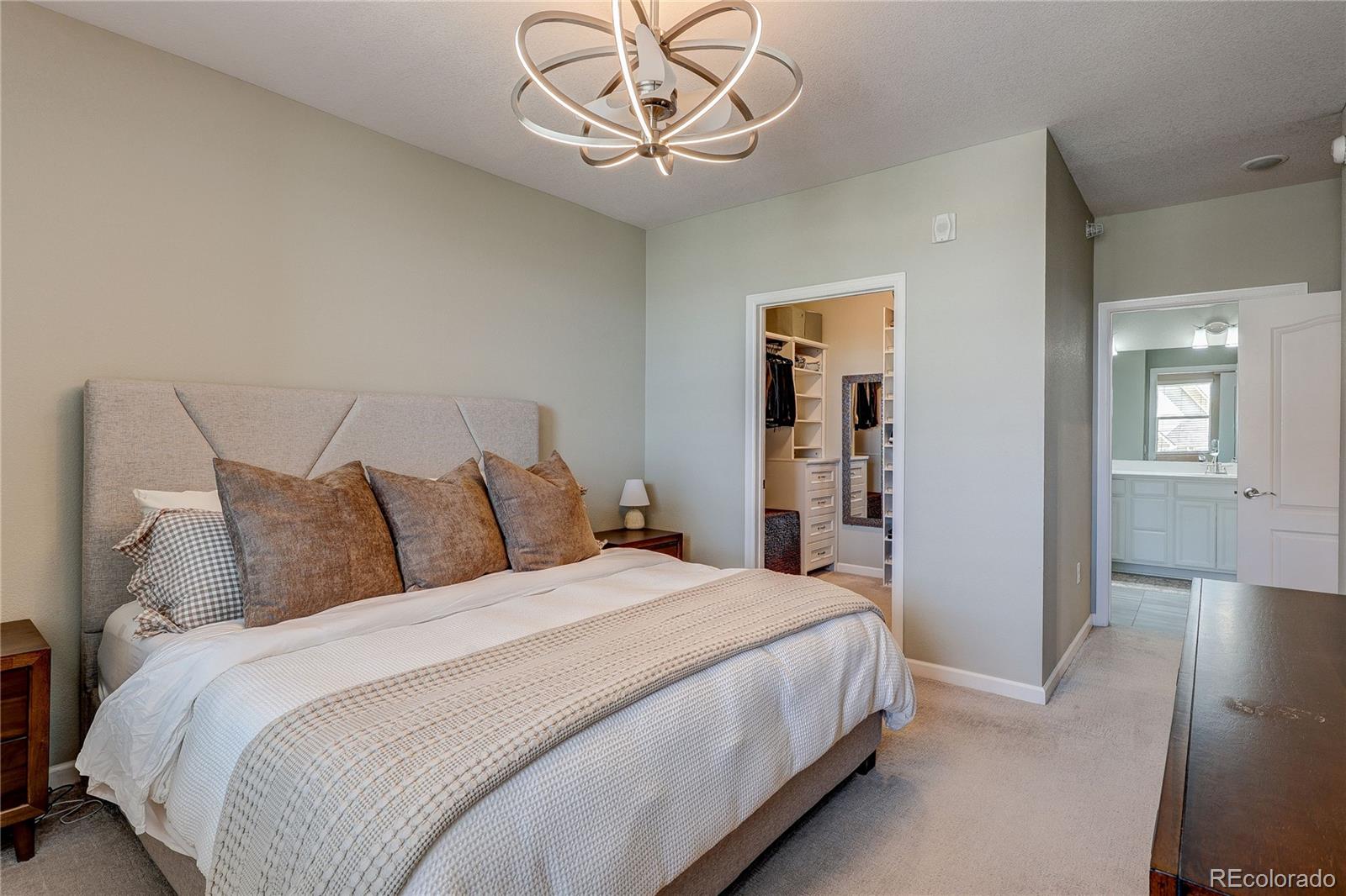 4777 Copeland Circle, Unit 204 Highlands Ranch, CO 80126 - Photo 16 of 39 a bedroom with bed and a chandelier
