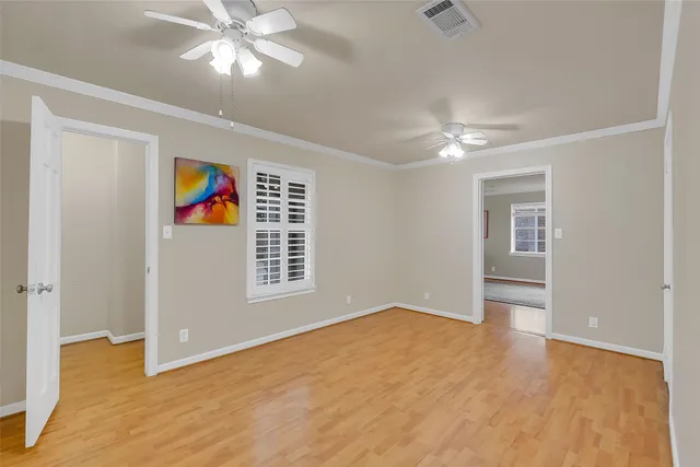 a view of an empty room with window and chandelier fan