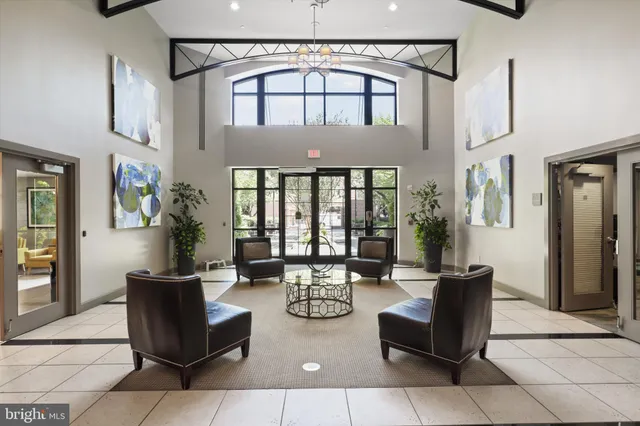a living room with couches a coffee table and potted plant with wooden floor