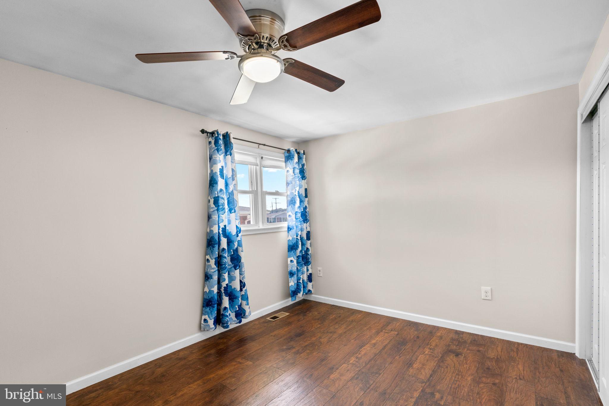 1221 Berkwood Road Baltimore, MD 21237 - Photo 12 of 34 an empty room with wooden floor chandelier fan and windows