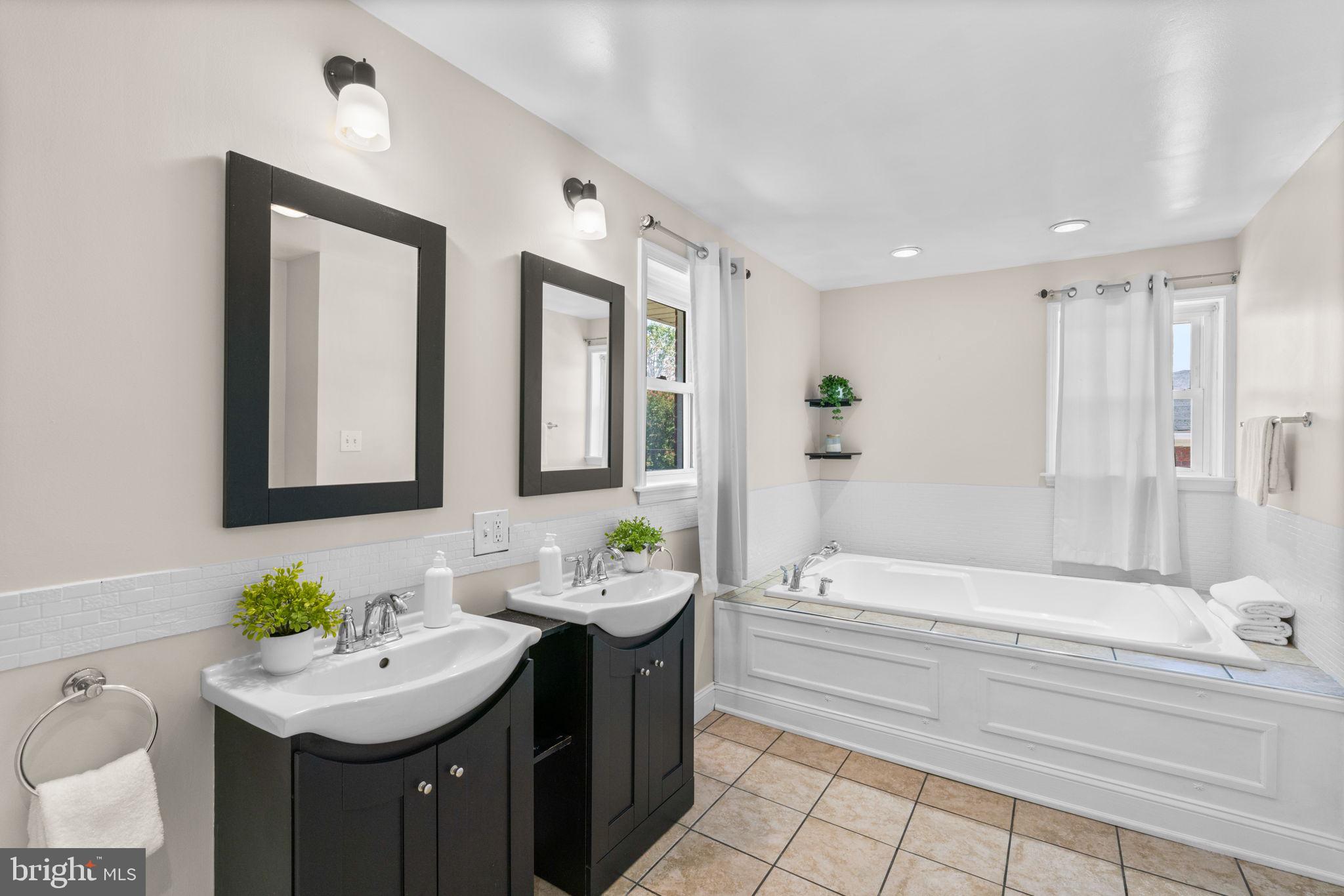 1221 Berkwood Road Baltimore, MD 21237 - Photo 16 of 34 a bathroom with a sink double vanity mirror and a bathtub