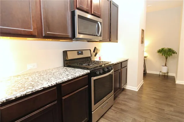 a kitchen with stainless steel appliances granite countertop a stove a sink and a microwave