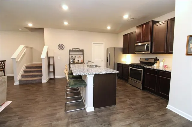 a kitchen with stainless steel appliances kitchen island granite countertop a stove a sink and a refrigerator