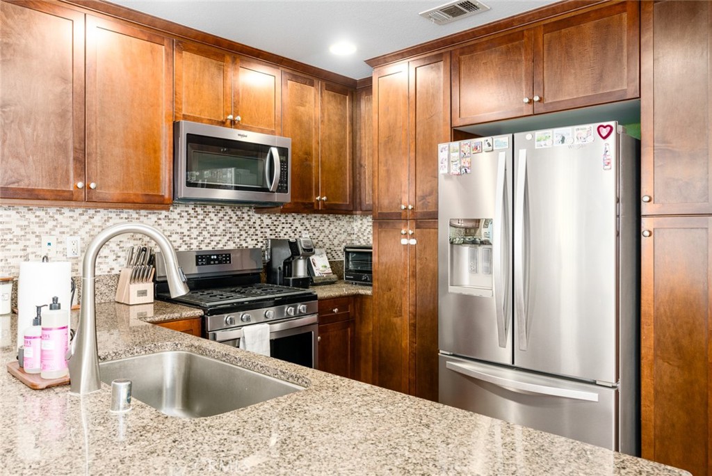 1113 Calabria Street Santee, CA 92071 - Photo 10 of 35 a kitchen with stainless steel appliances wooden cabinets a sink and a refrigerator