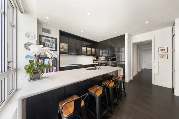 a kitchen with stainless steel appliances a dining table chairs refrigerator and sink