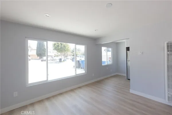 a view of an empty room with a window and wooden floor