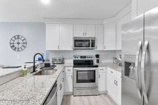 a kitchen with white cabinets and stainless steel appliances