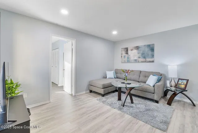 a living room with furniture and flowers with wooden floor
