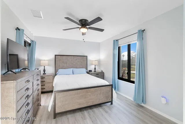 a spacious bedroom with a bed and a flat screen tv