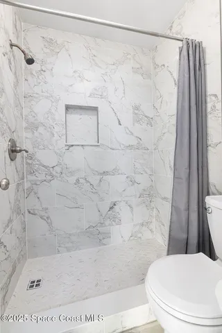 a white toilet sitting next to a shower curtain