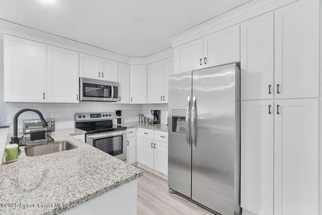 a kitchen with stainless steel appliances granite countertop a refrigerator sink and stove
