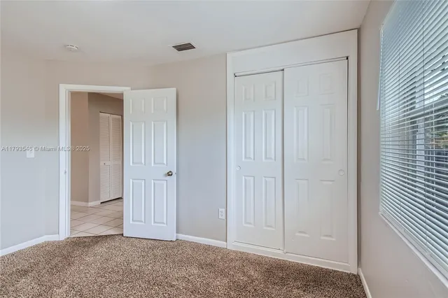 an empty room with closet and a chandelier fan