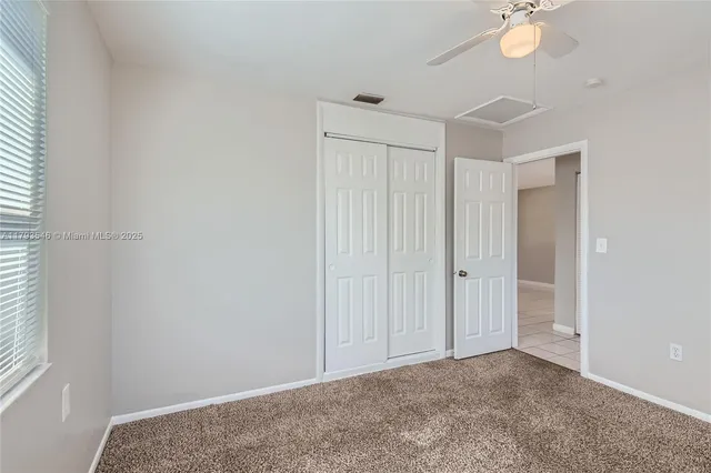an empty room with windows and ceiling fan