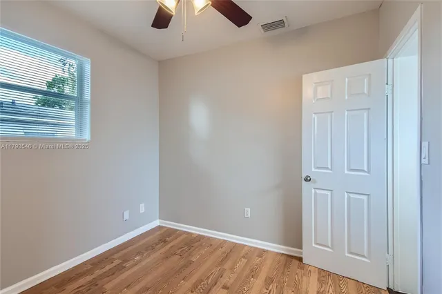 a view of wooden floor and a chandelier fan in a room
