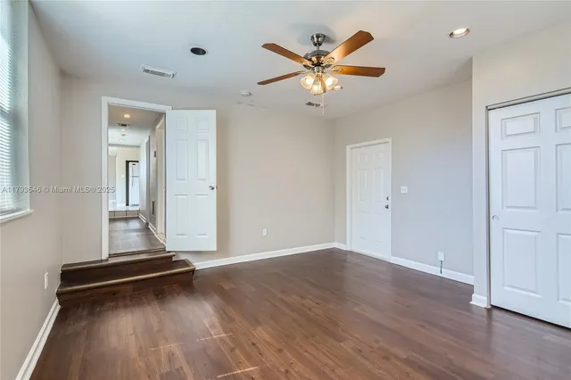 a backyard of a house with a large tree and wooden fence