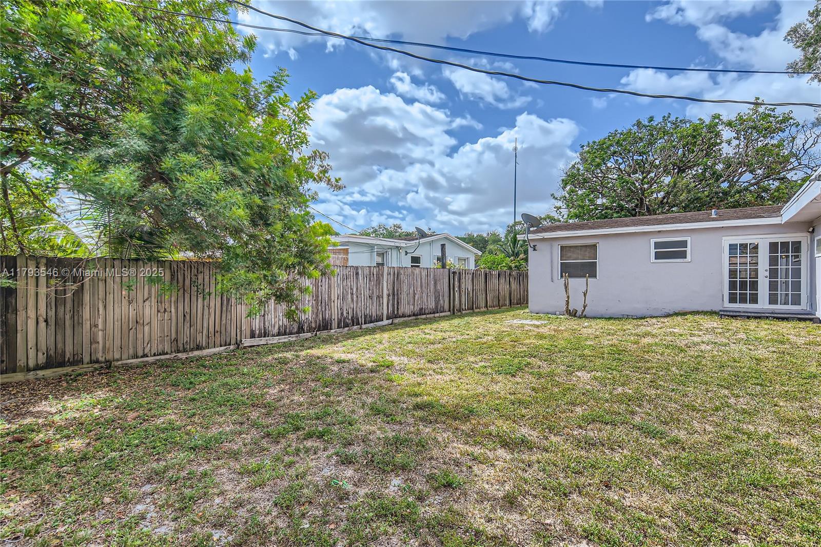 6437 Custer Street Hollywood, FL 33024 - Photo 21 of 22 a backyard of a house with a large tree and wooden fence