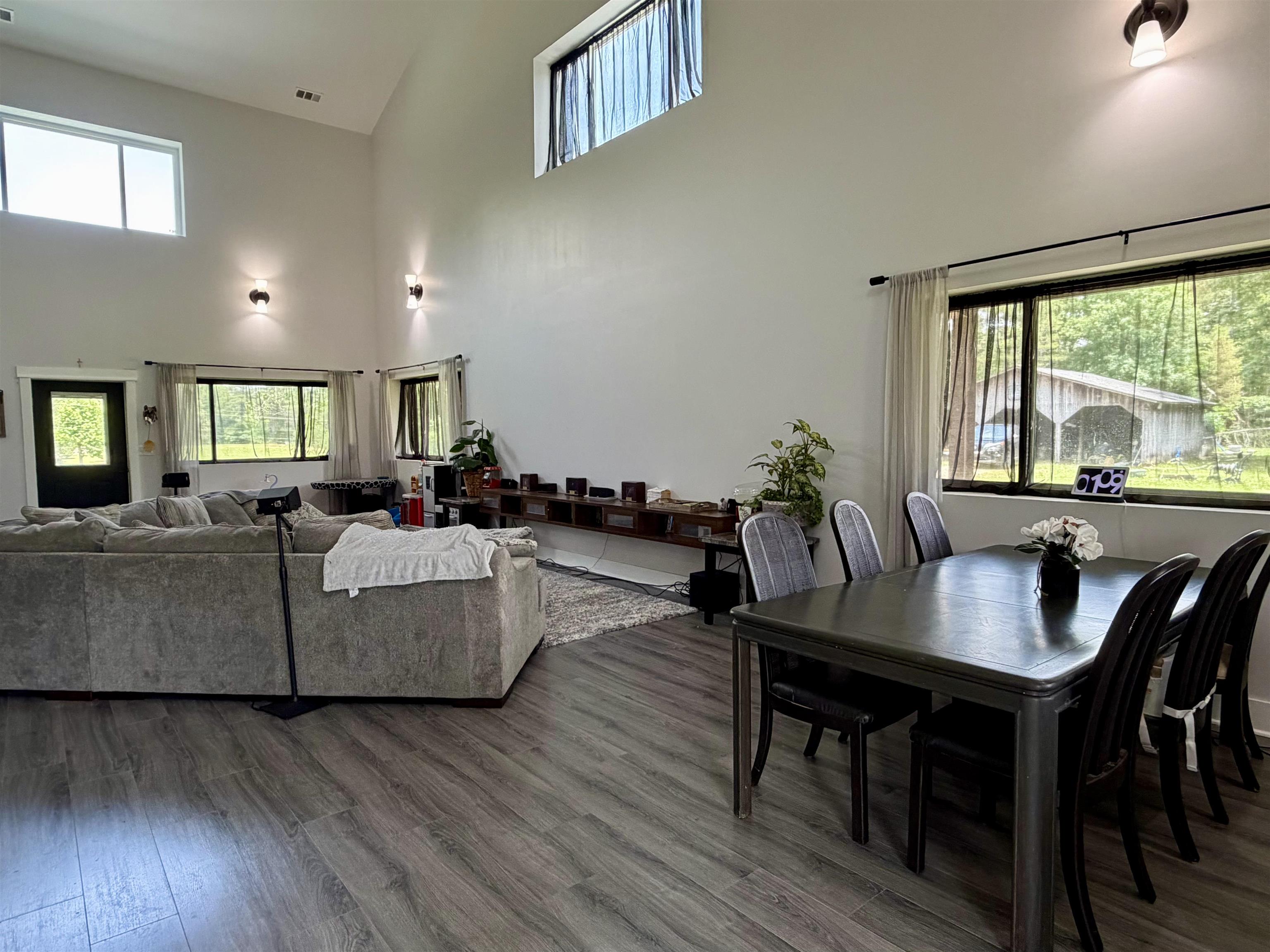3670 Peavine Road Middleton, TN 38052 - Photo 4 of 36 Open-concept living space featuring vaulted ceilings, wood-finish flooring, ample natural light from multiple windows, and recessed wall sconces