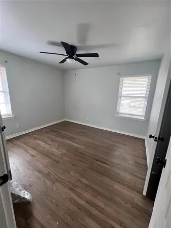 an empty room with wooden floor fan and windows