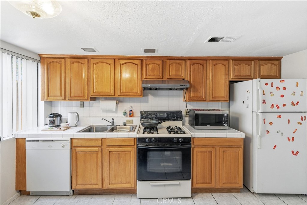 9471 Cortada Street El Monte, CA 91733 - Photo 9 of 27 a kitchen with stainless steel appliances granite countertop a stove a sink and a refrigerator