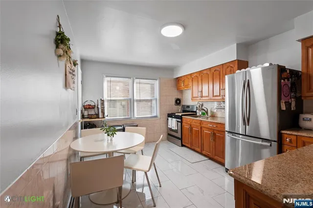 a kitchen with stainless steel appliances granite countertop a refrigerator a sink a stove a dining table and chairs