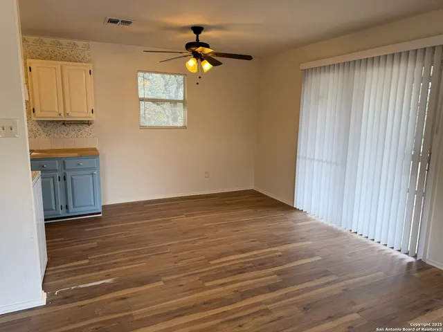 an empty room with wooden floor fan and windows