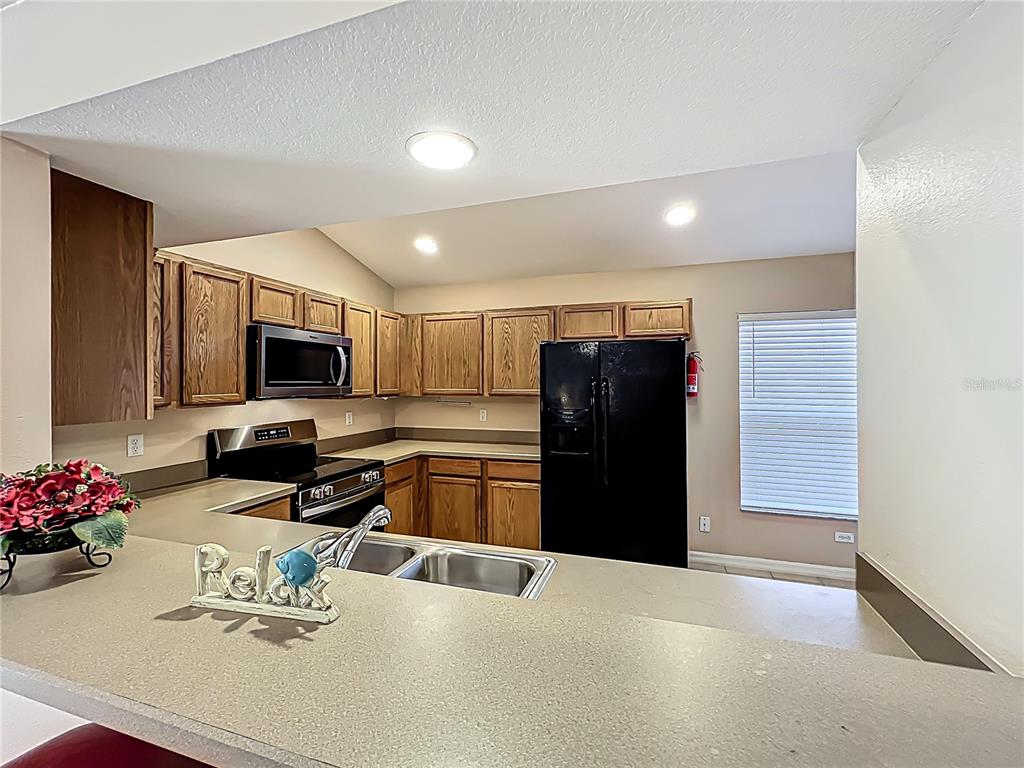 420 Robin Road Davenport, FL 33896 - Photo 12 of 29 a kitchen with a refrigerator and a stove top oven