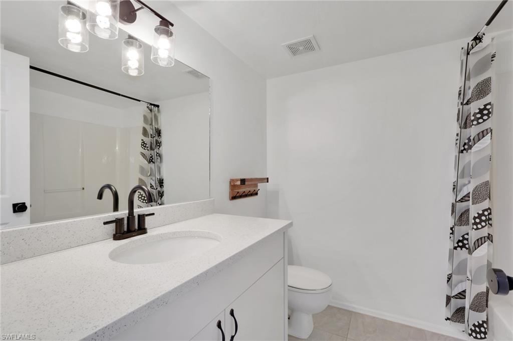 146 Cypress Way East, Unit 7 Naples, FL 34110 - Photo 22 of 27 a bathroom with a sink a toilet a mirror and shower